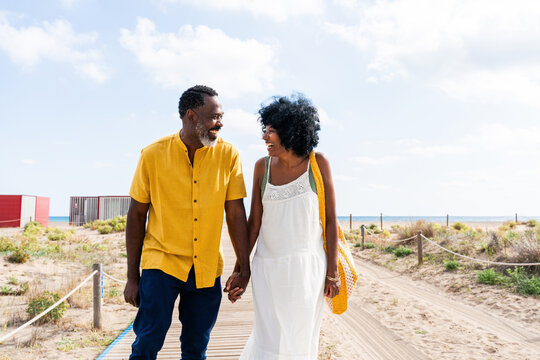 Beautiful mature black couple of lovers dating at the seaside - African senior man and woman bonding outdoors at summertime