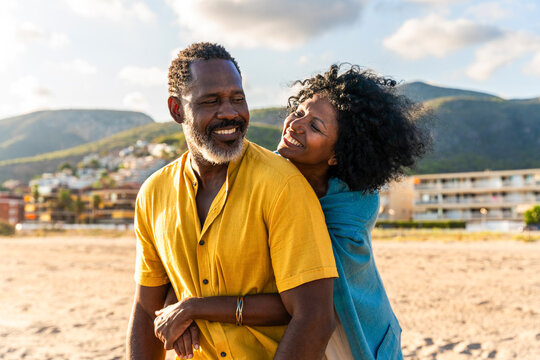Beautiful mature black couple of lovers dating at the seaside - African senior man and woman bonding outdoors at summertime