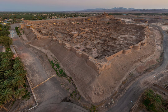 Aerial view of the ancient ruins of Arg-e Bam, a city of earthen architecture rising from the desert, bathed in the soft glow of the setting sun, Bam, Kerman Province, Iran.