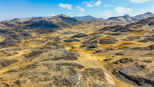 Aerial view of the rugged landscape where the earth unfolds in layers of ochre and charcoal, under a vast sky, Pajchanta, Qosqo, Peru.