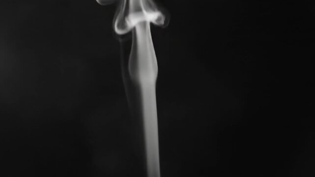 Video of slender smoke trail floating against dark studio background, minimal vapor movement visual for meditation, mystery, and conceptual storytelling media.