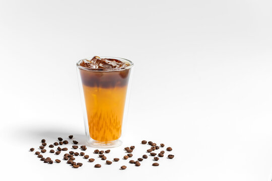 Refreshing bumble orange citrus juice and black coffee espresso drink with ice in a transparent double wall glass on white background 