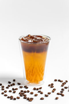 Refreshing bumble orange citrus juice and black coffee espresso drink with ice in a transparent double wall glass on white background 