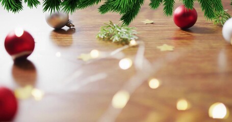 Displaying festive tabletop with evergreen garland, red and silver baubles, fairy lights on wood