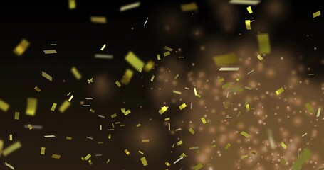 Falling gold confetti drifting across dark warm backdrop in studio, with glowing particles