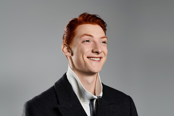 Stylish young man confidently showcasing modern fashion trends with a cheerful smile indoors