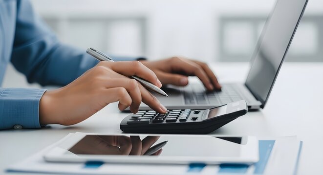 Business professional using calculator and laptop for budget planning, tax calculation and financial analysis, concept of accounting management and cash flow control.