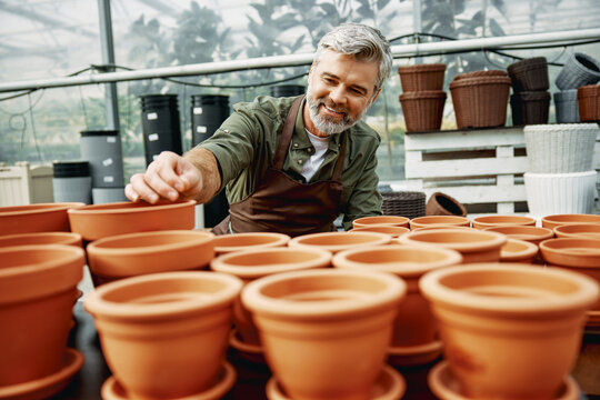 Gardener selecting terracotta pots in greenhouse nursery