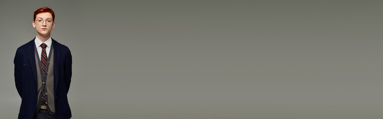 Stylish young man stands confidently in modern fashion against a muted background © LIGHTFIELD STUDIOS