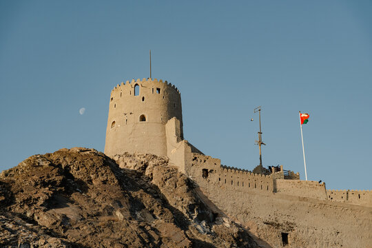 Muttrah Fort in Muscat Oman overlooking rocky mountain landscape at sunset