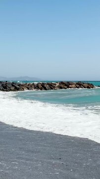 Resting on the beach with stormy turquoise waves of the sea in Almunecar, Spain, under dramatic skies and strong surf.