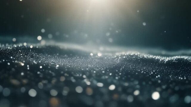 Sparkling glitter particles flow over dark undulating surface with bright light from above