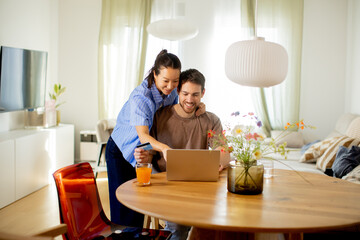 Obraz premium Couple works together on a laptop at home while enjoying drinks in the living room