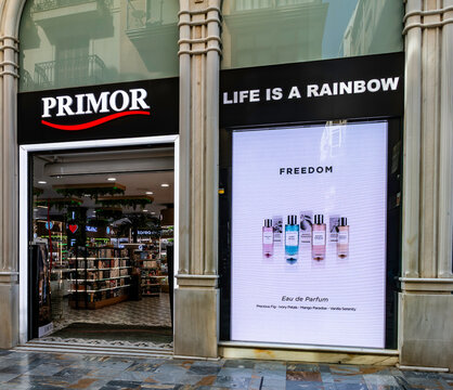 Primor store entrance in Cartagena, Spain, featuring "Life is a Rainbow" signage, an illuminated perfume advertisement, and ornate columns.