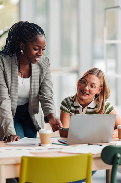 Diverse businesswomen collaborating using laptop in office