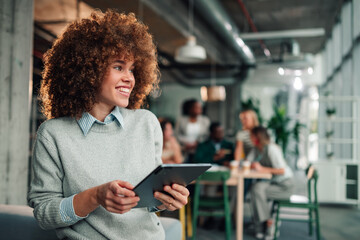Fototapeta na wymiar Businesswoman standing in modern office holding tablet smiling