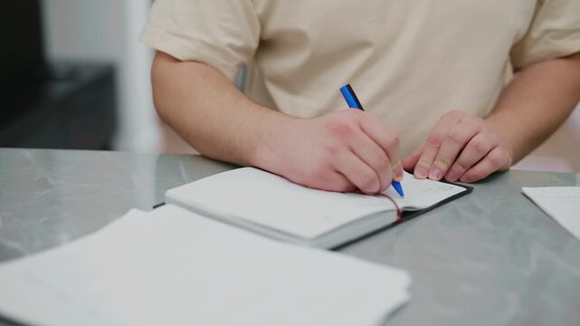 Male hands writing notes in notebook at table