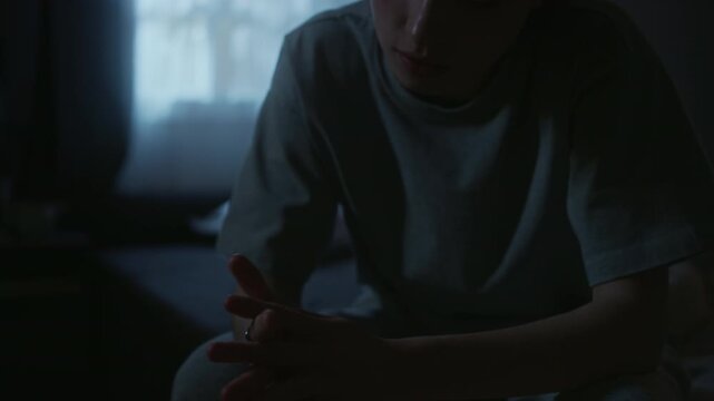 Tilt up shot of young adult woman rubbing eyes in exhaustion being awake at night while suffering from insomnia in dark bedroom