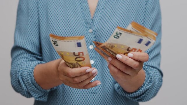 Several 50 euro notes are counted in large size in the foreground by female hands. Concept of saving money and thrift.