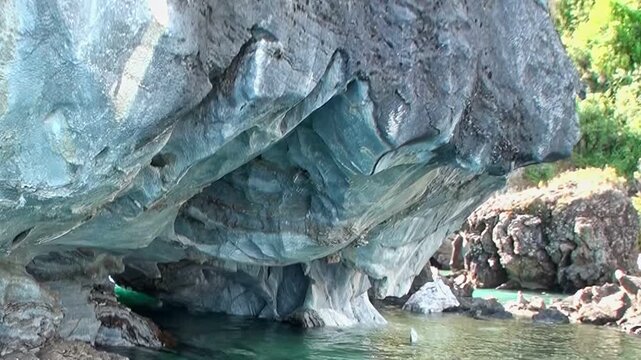 Witness ethereal beauty of Marble Caves in Patagonia. Gentle turquoise waters reflect stunning azure and grey rock formations, carved over millennia. Explore this natural marvel on bright, sunny day.