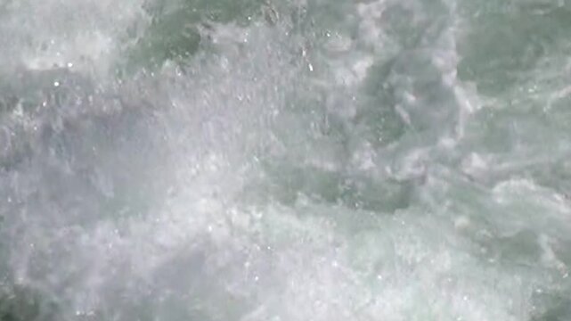 Water furiously surges and churns, creating foamy rapids on the Columbia River. The water moves with breathtaking aqueous energy, captured during the midday sun in July.