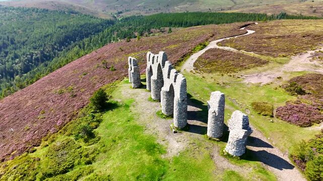 "Spectacular Drone Perspective of Fyrish Monument's Stone Arches Amidst Vibrant Purple Heather in the Scottish Highlands near Ross-shire."