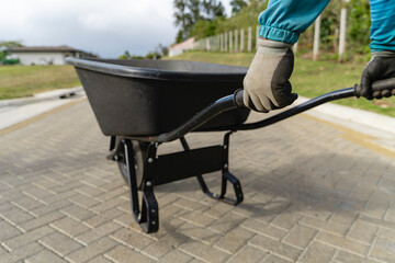 Worker pushing wheelbarrow on paved path in a cemetery