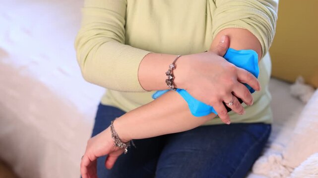 Woman with elbow and arm pain using cold ice pack gel at home.