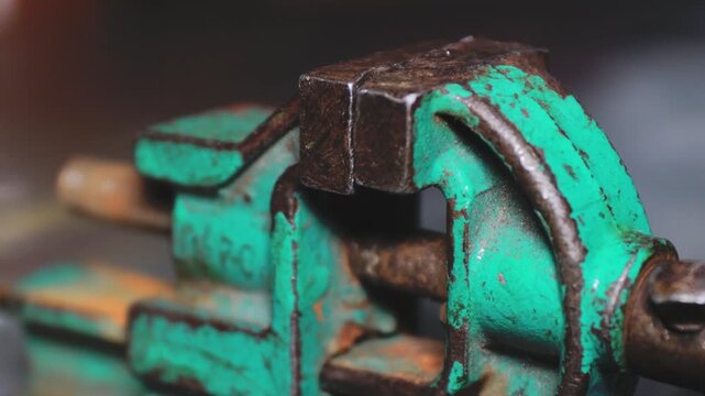 A detailed view of a green metal vise on a table, suitable for industrial or DIY settings