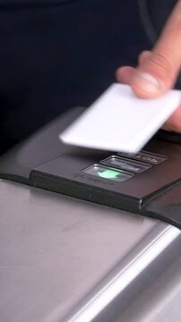 A hand gracefully taps a white access card onto a sleek, silver scanner. The device cycles through red and green lights, ultimately glowing emerald, signifying granted entry.