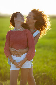 Mother and daughter smiling at each other at sunset