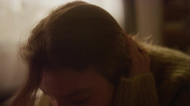 Close up portrait shot of young adult woman crying in bedroom holding head in despair then looking up at camera