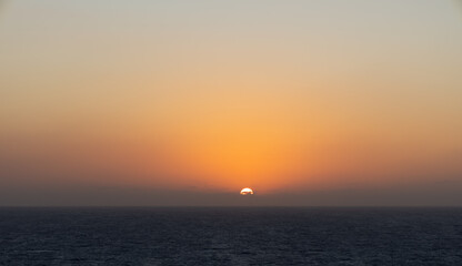 Obraz premium Golden sunset over ocean horizon with vibrant orange sky and calm sea