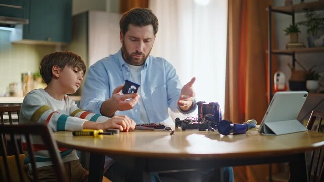 Father son assemble car sitting home kitchen desk closeup. Serious man boy