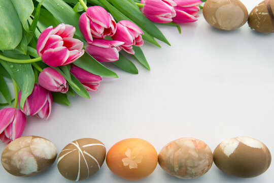 Easter background with bouquet of pink tulips and colorful eggs .