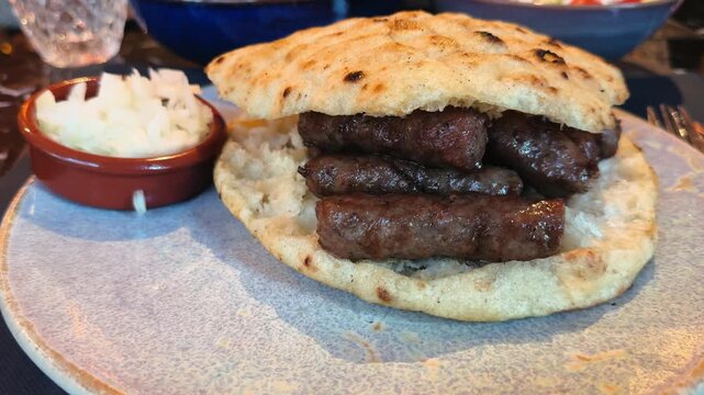Sausage Cevapcici, traditional juicy Balkan sausages made from ground beef, grilled, and served with onions in pita bread.
