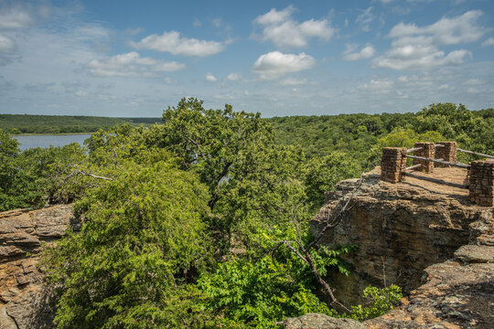 Fenced Off Viewpoint Overlooking Blue Lake Surrounded by Forest of Green Trees With Rocky Landscape in Lake Mineral Wells State Park in Mineral Wells, Texas