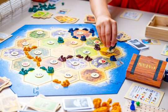 Playing popular strategy classic Catan board game, family enjoys quality time, Catan game tiles players plan moves in exciting tabletop competition, happy Family moment