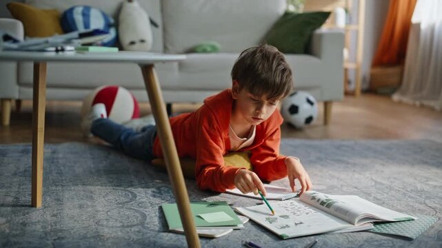 Preteen boy learning homework in living room closeup. Smart pupil reading task 