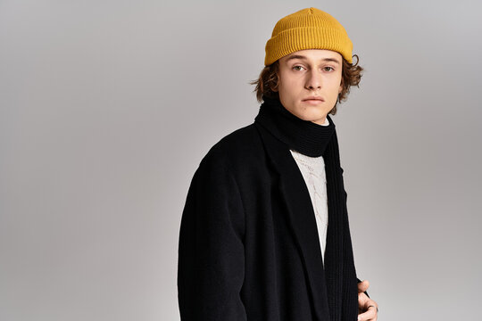 Stylish man exuding confidence in contemporary fashion with a vibrant yellow beanie and scarf