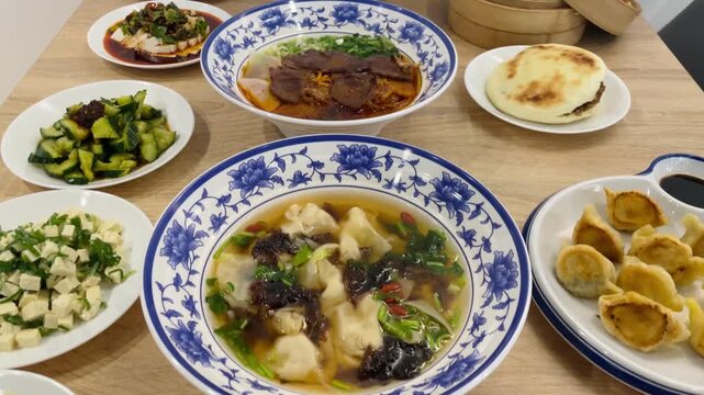 Close-up of Chinese cuisine dishes arranged on a dining table. Several plates with prepared meals are placed together for serving. Cafe, bistro or restaurant or dining setting. Lifestyle