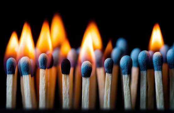 Fila de cerillas encendidas y apagadas sobre fondo negro; algunas arden con llamas brillantes mientras otras esperan intactas, creando un contraste dram&aacute;tico de luz, fuego y madera.