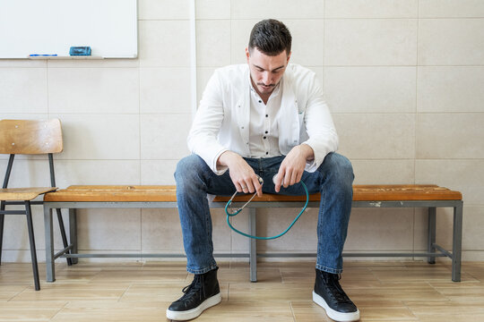 A tired doctor sits alone on a bench in the hallway after a long and demanding day. The quiet moment shows exhaustion and reflection after caring for many patients.	
