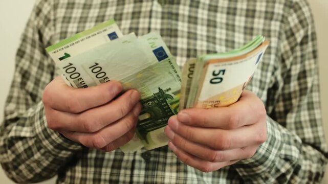 Man counting euro banknotes and taking one hundred euro bill from the stack before putting it aside. Concept of cash handling, budgeting, personal finance and money management
