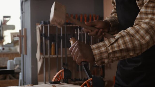 carpenter using a wooden mallet and chisel to carve a piece of wood