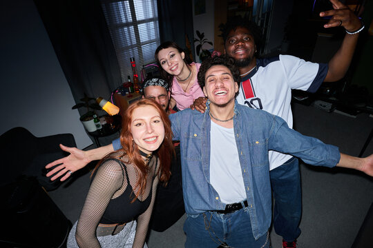 Group of diverse young people smiling and posing for selfie in living room, showing cheerful expressions and casual gestures, multiethnic friends enjoying time together indoors