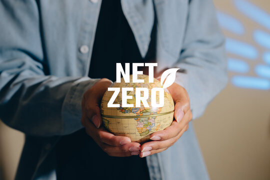 Net zero concept, hands holding globe with environmental message, carbon reduction commitment, climate action strategy, sustainable business transition, global decarbonization goal