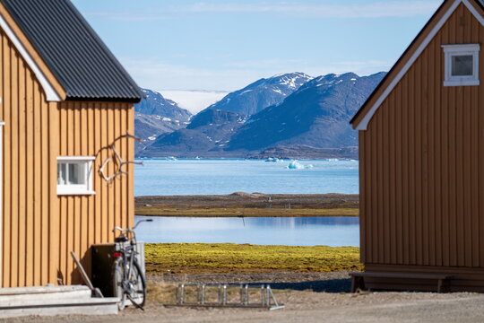 Bicycle parked beside a building at the research station at Ny Alesund, Svalbard, Norway, with a bay and snow covered mountains in the distance