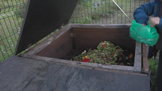 Person throwing organic food waste into a compost bin
