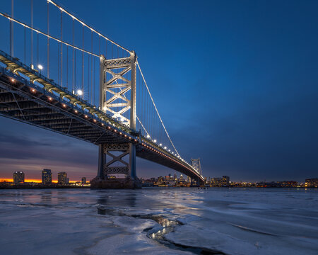Ben Franklin Bridge and Philadelphia skyline at sunset with frozen Delaware River